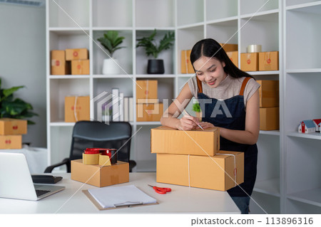 Woman asian in an online store check the customer address and write the information on the box. Online shopping concept Woman asian in an online store check the customer address and write the information on the box. Online shopping concept 113896316