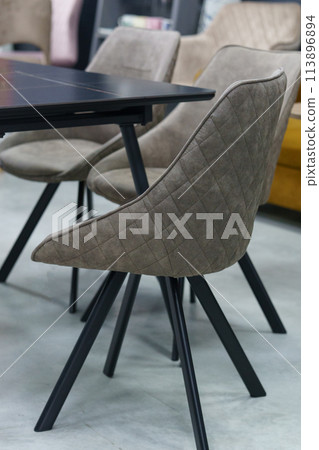 Black wooden table complete with beige wooden chairs with soft fabric upholstery. White candle on the table 113896894