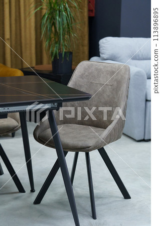 Black wooden table complete with beige wooden chairs with soft fabric upholstery. White candle on the table Black wooden table complete with beige wooden chairs with soft fabric upholstery. White candle on the table 113896895