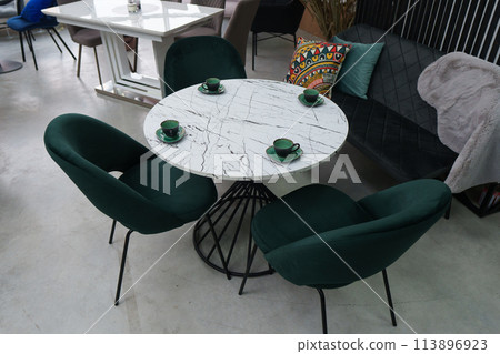 White wooden table complete with green wooden chairs with soft fabric upholstery. Green cups on the table White wooden table complete with green wooden chairs with soft fabric upholstery. Green cups on the table 113896923