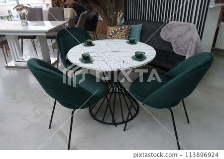 White wooden table complete with green wooden chairs with soft fabric upholstery. Green cups on the table White wooden table complete with green wooden chairs with soft fabric upholstery. Green cups on the table 113896924