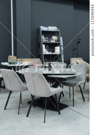 Gray wooden table complete with gray wooden chairs with soft fabric upholstery. Black glass jar with incense sticks on the table Gray wooden table complete with gray wooden chairs with soft fabric upholstery. Black glass jar with incense sticks on the table 113896948
