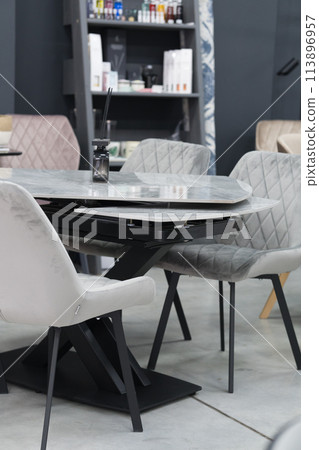 Gray wooden table complete with gray wooden chairs with soft fabric upholstery. Black glass jar with incense sticks on the table Gray wooden table complete with gray wooden chairs with soft fabric upholstery. Black glass jar with incense sticks on the table 113896957