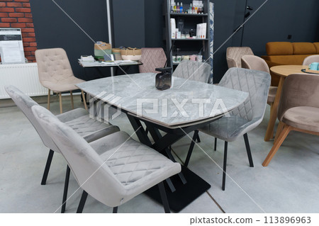 Gray wooden table complete with gray wooden chairs with soft fabric upholstery. Black glass jar with incense sticks on the table 113896963