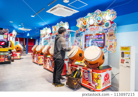 A man playing Taiko no Tatsujin at an arcade 113897215