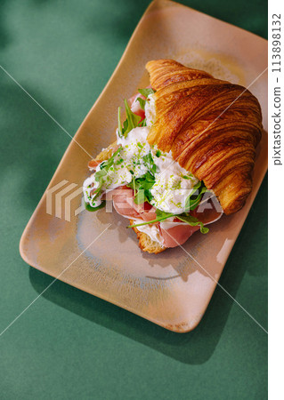 Gourmet croissant sandwich with prosciutto and arugula Gourmet croissant sandwich with prosciutto and arugula 113898132