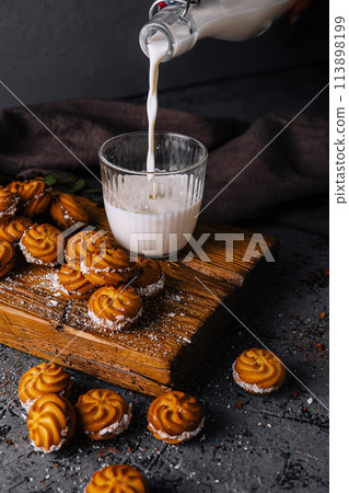 Pouring milk into glass beside freshly baked cookies Pouring milk into glass beside freshly baked cookies 113898199