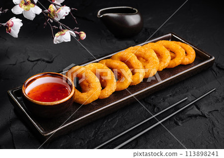Crispy fried onion rings with dipping sauce on dark background 113898241