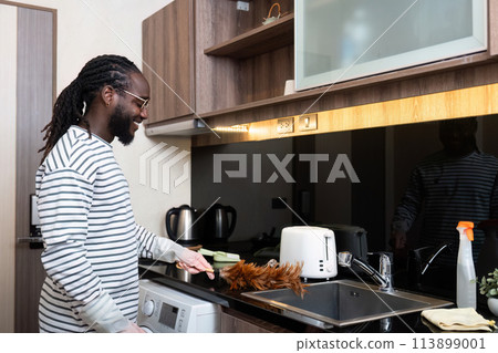 African American man young use duster cleaning in kitchen at home 113899001