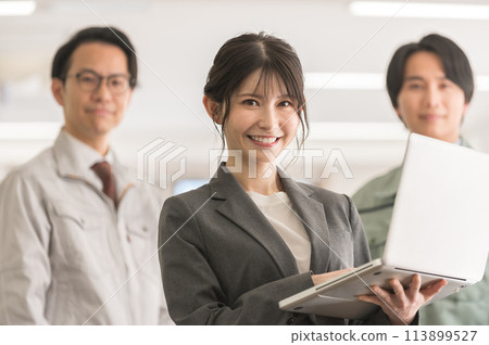 A woman in a suit with a laptop and a male engineer in work clothes 113899527