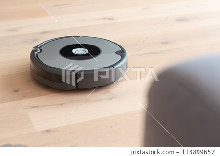 robot vacuum cleaner cleaning a wooden floor robot vacuum cleaner cleaning a wooden floor 113899657