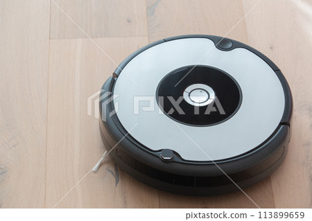 robot vacuum cleaner cleaning a wooden floor robot vacuum cleaner cleaning a wooden floor 113899659