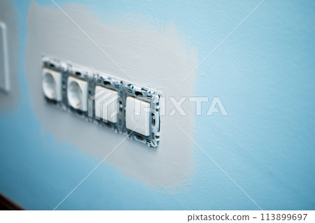 Preparation work to paint the wall of the house, edging the sockets before rolling the roller 113899697