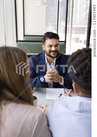 Cheerful young Indian consultant man meeting with couple 113901465