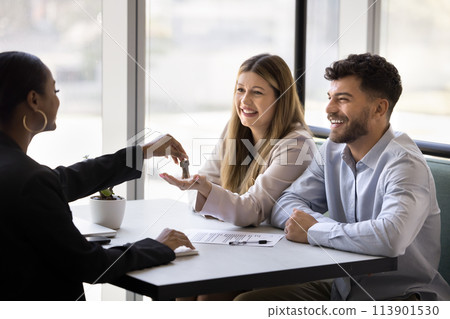 Happy diverse couple of clients getting key from African realtor Happy diverse couple of clients getting key from African realtor 113901530