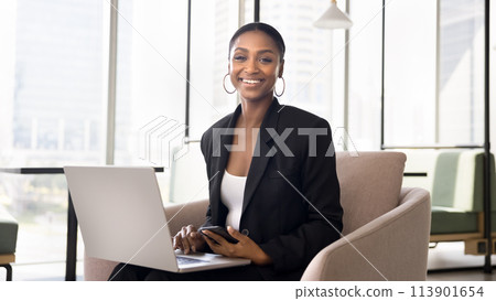 Happy African American professional woman in formal suit holding laptop Happy African American professional woman in formal suit holding laptop 113901654