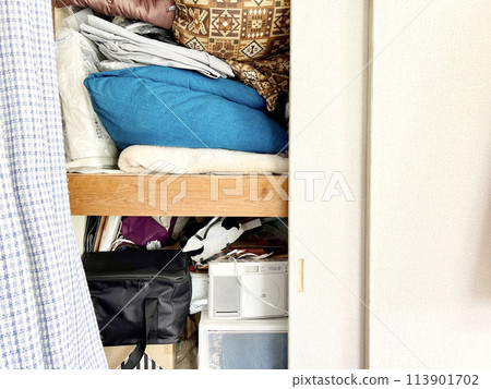 Front of a closet with futons on the top shelf and household items on the bottom shelf Front of a closet with futons on the top shelf and household items on the bottom shelf 113901702