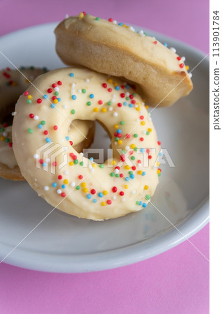 Small homemade donuts covered in white chocolate and colorful toppings Small homemade donuts covered in white chocolate and colorful toppings 113901784