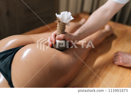 Top view of Herbal Ayurvedic massage with Kizhi Herbal Bags on buttocks. Relaxed female client receiving herbal bolus bags massage. Tranquil and serenity of aromatherapy recreation at spa salon. 113901873