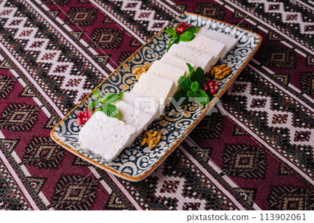 Traditional white cheese platter on ornate textile 113902061