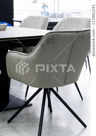 Gray wooden table combined with gray chairs with soft fabric upholstery. There is a black porcelain plate on the table 113902241