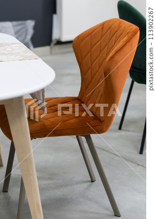 White wooden table combined with orange wooden chairs with soft fabric upholstery. There is a white delivery with a multi-colored bouquet of flowers on the table White wooden table combined with orange wooden chairs with soft fabric upholstery. There is a white delivery with a multi-colored bouquet of flowers on the table 113902267