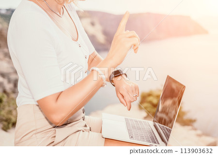 Digital nomad, Business woman working on laptop by the sea. Pretty lady typing on computer by the sea at sunset, makes a business transaction online from a distance. Freelance, remote work on vacation Digital nomad, Business woman working on laptop by the sea. Pretty lady typing on computer by the sea at sunset, makes a business transaction online from a distance. Freelance, remote work on vacation 113903632