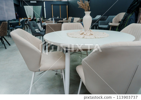 White wooden table complete with white wooden chairs with soft fabric upholstery. Milky porcelain vase on the table White wooden table complete with white wooden chairs with soft fabric upholstery. Milky porcelain vase on the table 113903737