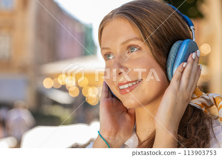 Happy teenager girl in wireless headphones choosing, listening music dancing outdoors city street Happy teenager girl in wireless headphones choosing, listening music dancing outdoors city street 113903753