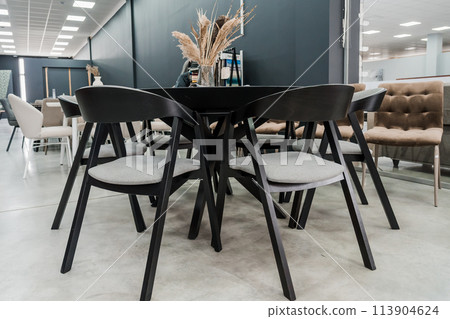 Black wooden table complete with black wooden chairs with soft gray fabric upholstery. Glass vase on the table 113904624