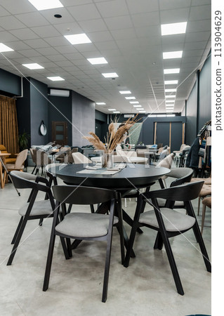 Black wooden table complete with black wooden chairs with soft gray fabric upholstery. Glass vase on the table Black wooden table complete with black wooden chairs with soft gray fabric upholstery. Glass vase on the table 113904629