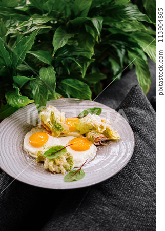Gourmet eggs benedict on plate with greens 113904865