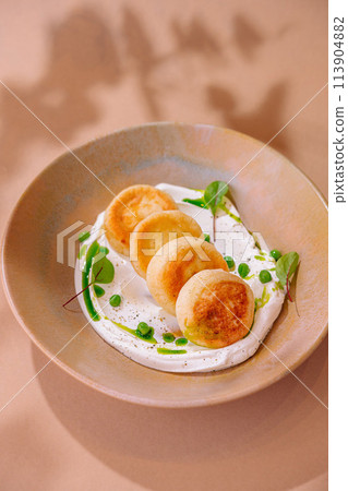 Gourmet cottage cheese pancakes on creamy sauce with greens Gourmet cottage cheese pancakes on creamy sauce with greens 113904882