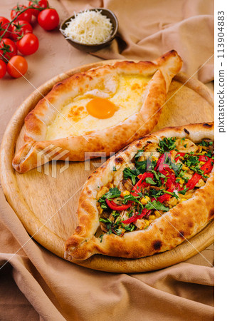 Traditional adjarian and megrelian khachapuri on wooden board Traditional adjarian and megrelian khachapuri on wooden board 113904883