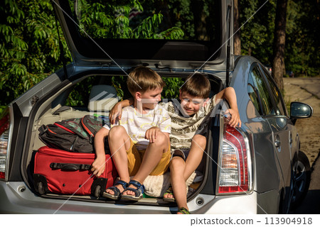 Two cute boys sitting in a car trunk before going on vacations with their parents. Two kids looking forward for a road trip or travel. Summer break at school. Family travel by car Two cute boys sitting in a car trunk before going on vacations with their parents. Two kids looking forward for a road trip or travel. Summer break at school. Family travel by car 113904918