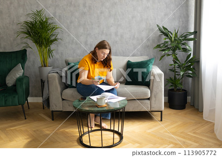 The 30s woman considers the costs of gas, electricity, heating. The concept of increasing tariffs for services. Woman with financial bills calculating on smart phone. Debt, bankruptcy The 30s woman considers the costs of gas, electricity, heating. The concept of increasing tariffs for services. Woman with financial bills calculating on smart phone. Debt, bankruptcy 113905772