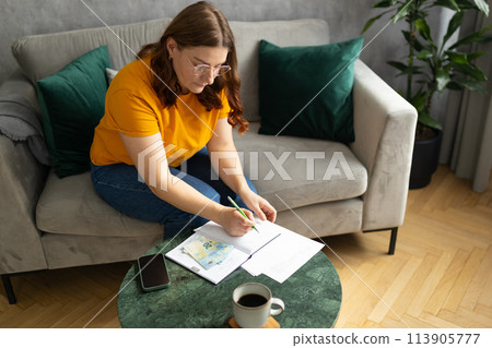 The 30s woman considers the costs of gas, electricity, heating. The concept of increasing tariffs for services. Woman with financial bills calculating on smart phone. Debt, bankruptcy 113905777