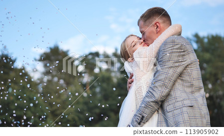 The bride and groom toss confetti above them and embrace. 113905902