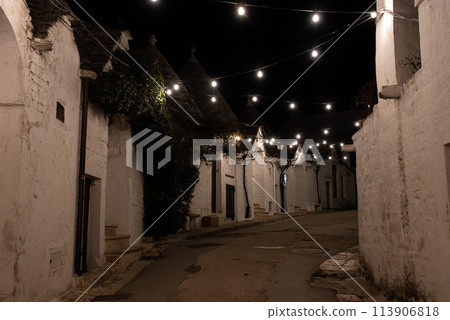 Scenic abandoned street in the Trulli district of Alberobello, Italy 113906818