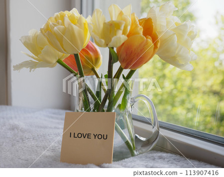Bouquet of bright flowers standing in a vase on the table 113907416