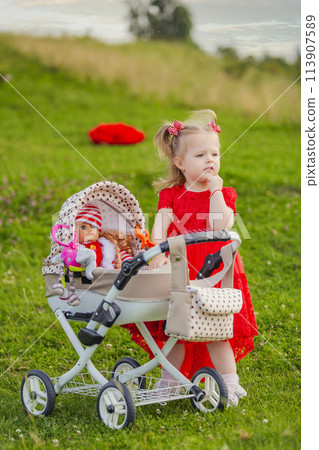 little girl plays with a doll and a stroller 113907589