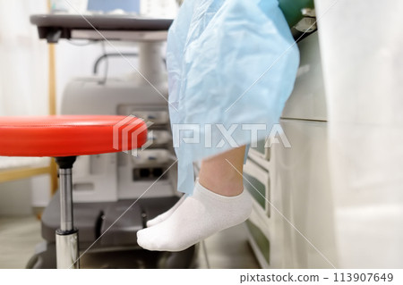 A young woman at a mammologist's appointment for examination of mammary glands and lymph nodes. Patient waiting of gynecological ultrasound exam. A young woman at a mammologist's appointment for examination of mammary glands and lymph nodes. Patient waiting of gynecological ultrasound exam. 113907649