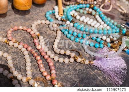 A variety of rosary with gemstone beads lies on the counter of a street market 113907673