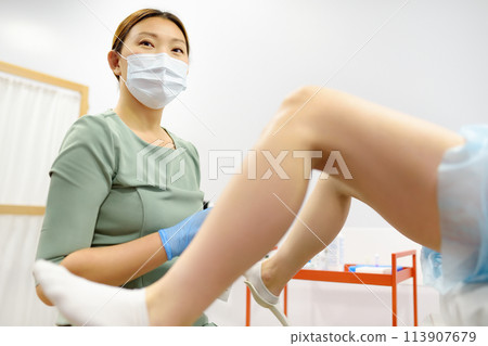 Gynecologist examines a patient laying on gynecological chair using medical vaginal speculum. Doctor takes a smear from a young woman cervix. Diagnosis of diseases. 113907679