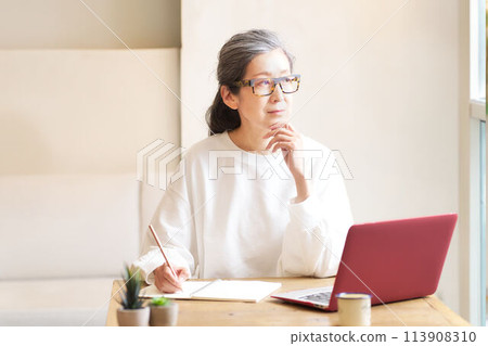 A middle-aged woman with gray hair studying at home 113908310