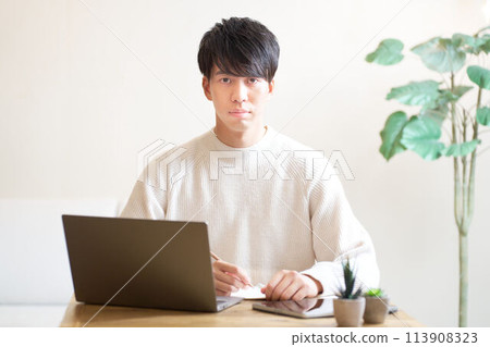 Young man sitting at desk and looking away 113908323