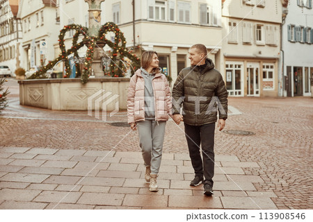 Loving couple of tourists walking around old town. Couple of lovers leisurely stroll in the cool autumn morning on the streets of a BIETIGHEIM-BISSINGEN (Germany). The guy holds his wife. Vacation 113908546