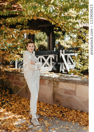 Beautiful elegant woman standing in autumn park with yellow leaves outdoor. Beauty Romantic Girl Outdoors enjoy autumn yellow leaves. Portrait of joyful woman in park during fall. Happy ng nature. Sun Beautiful elegant woman standing in autumn park with yellow leaves outdoor. Beauty Romantic Girl Outdoors enjoy autumn yellow leaves. Portrait of joyful woman in park during fall. Happy ng nature. Sun 113908623