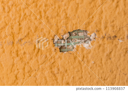 Hole in the wall close-up ruined broken damaged construction texture of bright yellow surface Hole in the wall close-up ruined broken damaged construction texture of bright yellow surface 113908837
