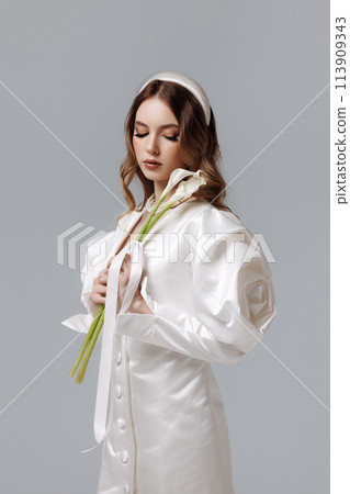 A woman in a white dress holding a flower A woman in a white dress holding a flower 113909343
